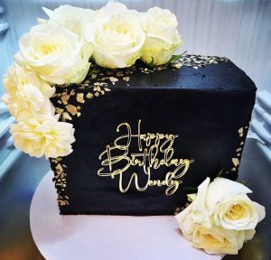 40th Birthday black and gold cake with fresh cream flowers