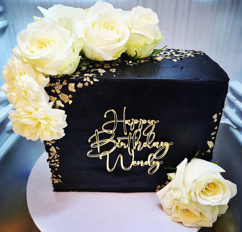 40th Birthday black and gold cake with fresh cream flowers